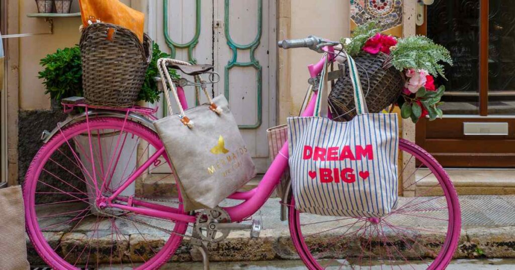 bicicletta rosa con borse shopper in primo piano