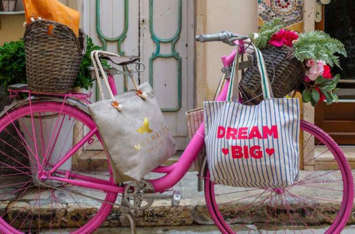 bicicletta rosa con borse shopper in primo piano